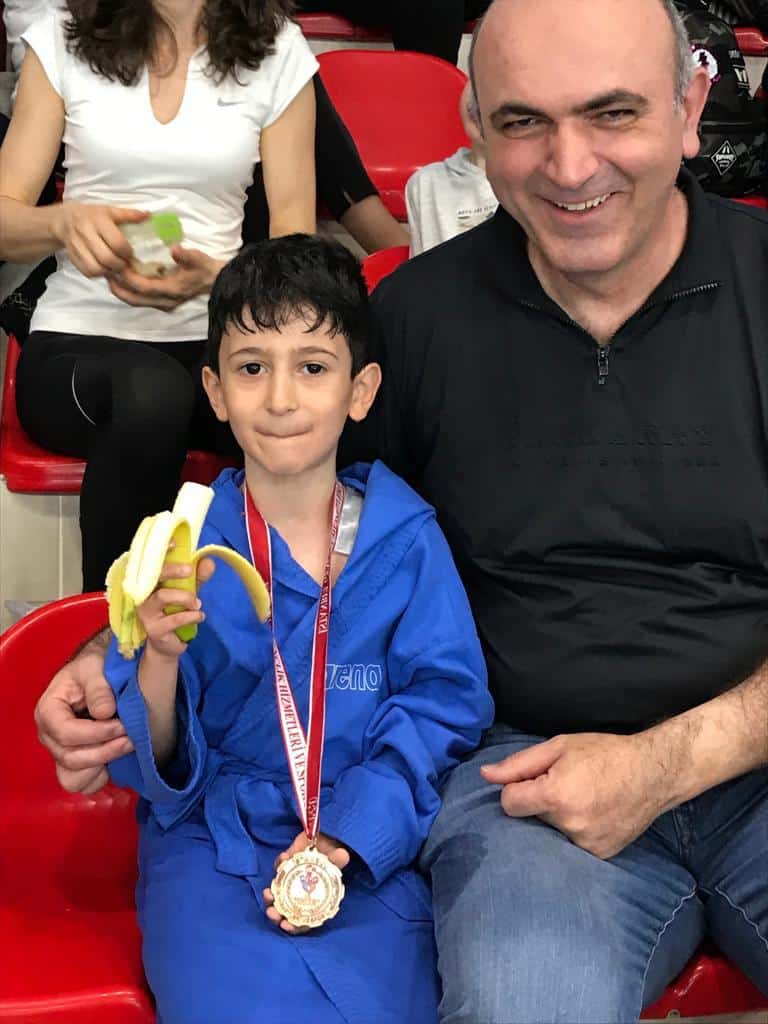 Umut’un ilk yüzme yarışının ardından madalyası boynunda ve elinde muzla tribünde çekilen fotoğrafı