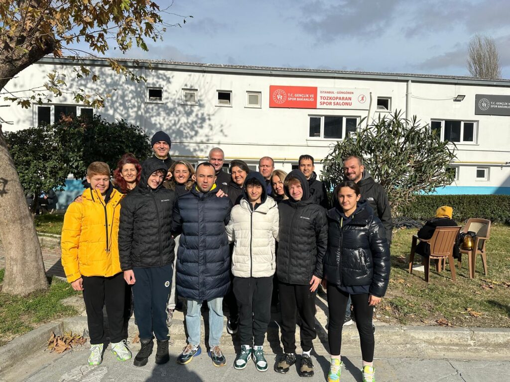 Tozkoparan Spor Salonu önünde Fenerbahçeli genç yüzücüler, antrenörleri ve aileleriyle birlikte çekilmiş toplu fotoğraf.